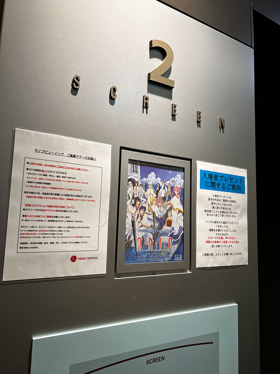 TOHOシネマズ上野、スクリーン２入口脇に掲示された『ARIA the BENEDIZIONE』チラシと舞台挨拶ライブビューイングについての諸注意。