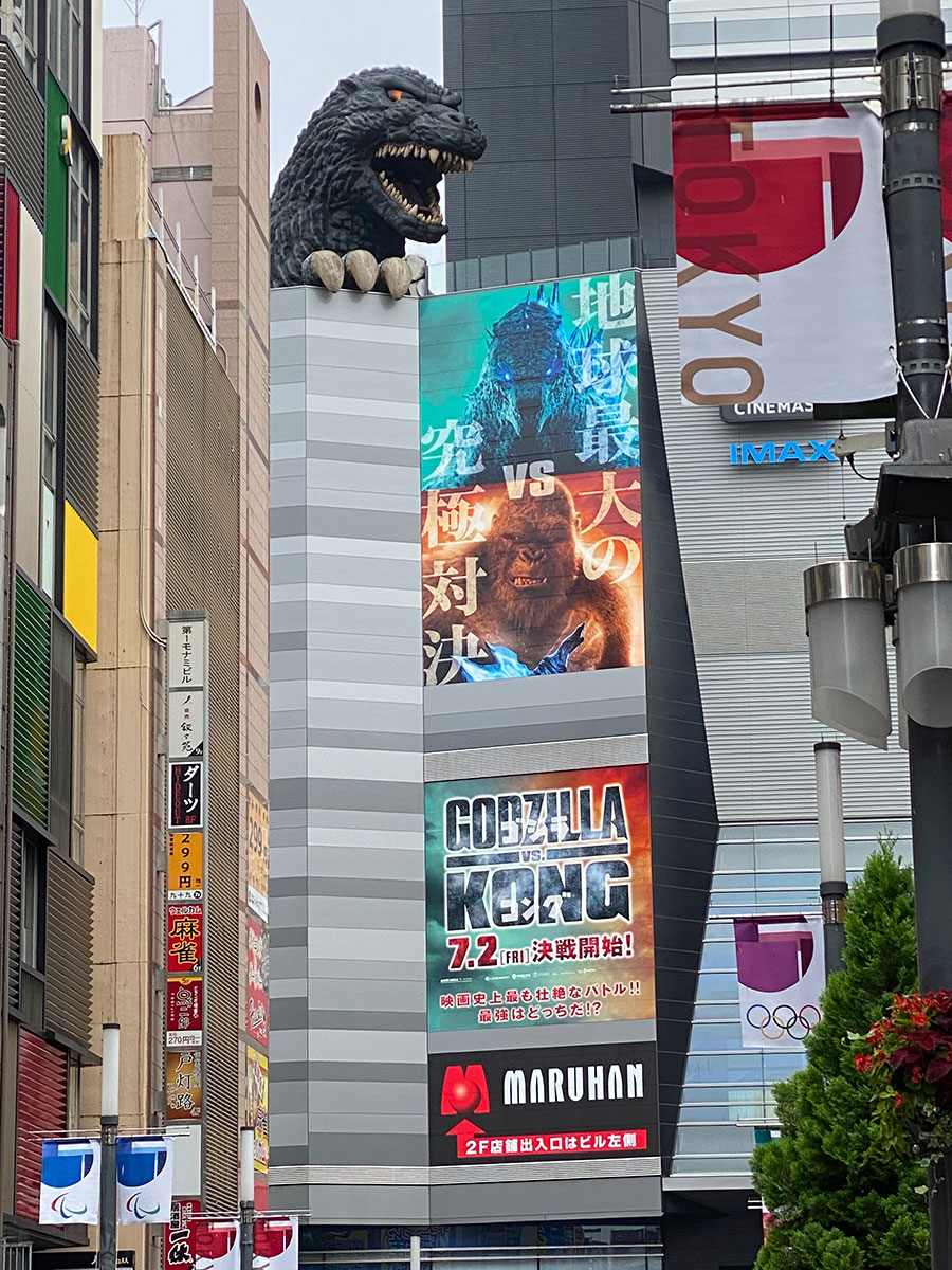 TOHOシネマズ新宿が入っている新宿東宝ビル壁面にあしらわれた『ゴジラvsコング』キーヴィジュアルと、それを見下ろすゴジラヘッド、。