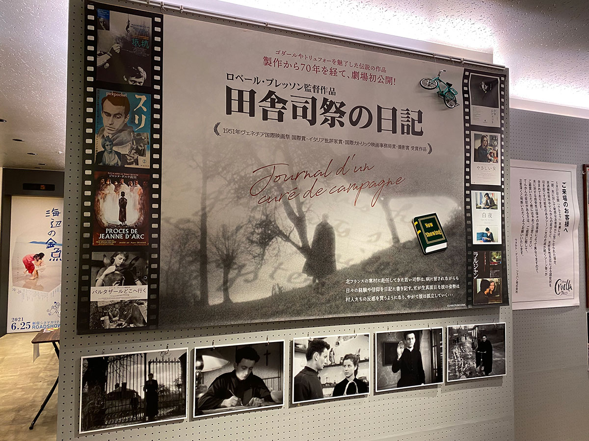 新宿シネマカリテ、ロビーに展示された『田舎司祭の日記』イメージヴィジュアルと場面写真、およびロベール・ブレッソン監督作品のキーヴィジュアル。